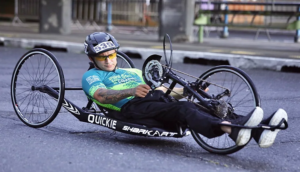 Atleta pilota uma handbike em alta velocidade numa avenida.